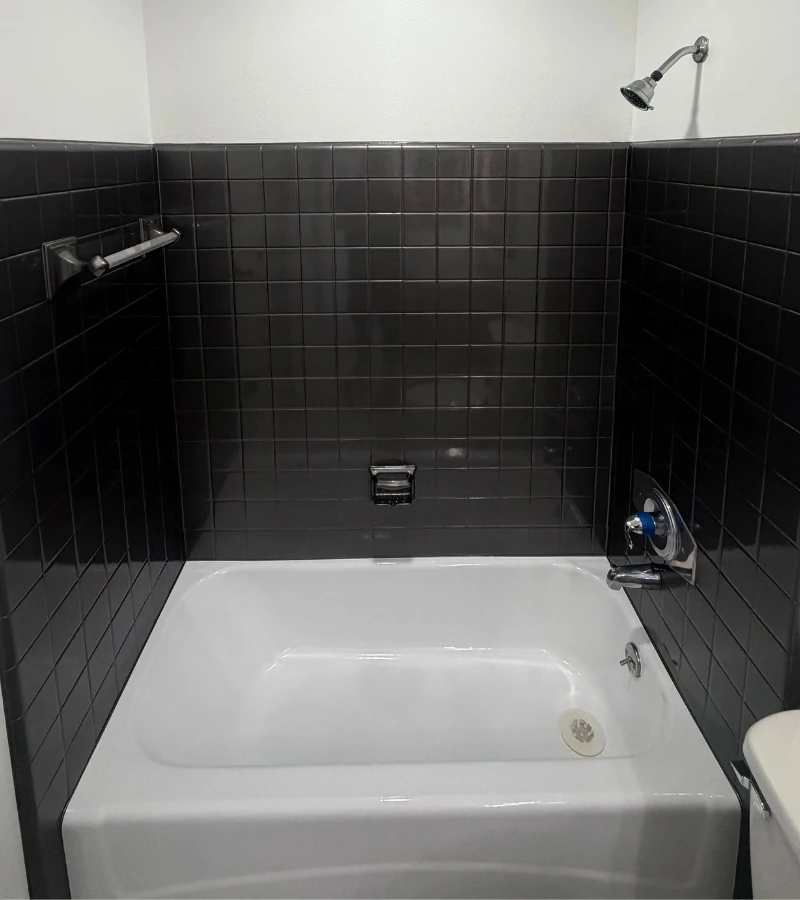 Completed bathtub and black tile reglazing service in Kissimmee by Castillo Epoxy Refinishing.