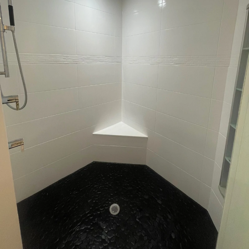black-pebble-shower-floor-reglazing-after-kissimmee. Refinished black pebble shower floor and white wall tiles in Kissimmee FL