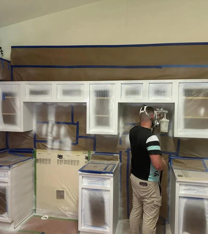 Kitchen cabinet frames meticulously masked with paper and blue tape prior to professional painting by Castillo Epoxy.